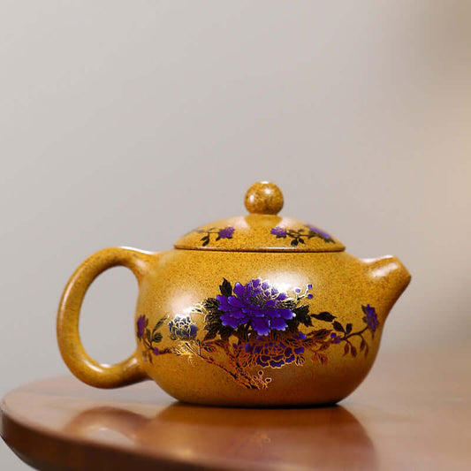 Handmade Yixing purple sand teapot with floral design, showcasing vibrant purple flowers on a golden surface.