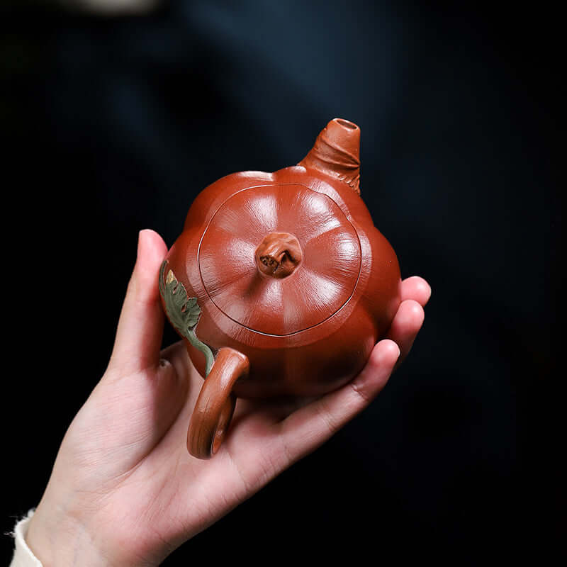 Handmade Yixing purple sand teapot shaped like a pumpkin, showcasing elegant design and craftsmanship.
