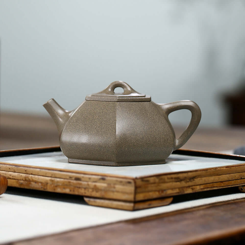 Handmade Yixing purple sand teapot on a wooden tray, showcasing unique craftsmanship and elegant design.