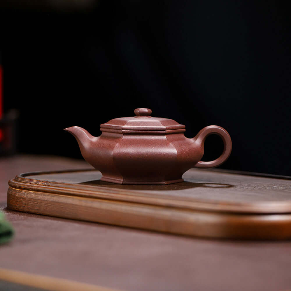 Handmade Yixing purple sand teapot on a wooden tray, showcasing its craftsmanship and elegant design.