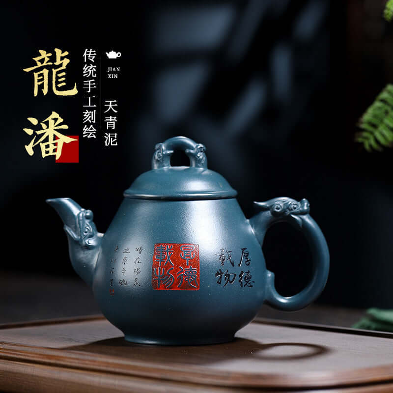 Handmade Yixing purple sand teapot in dark blue finish, featuring traditional engraving and unique dragon handles.