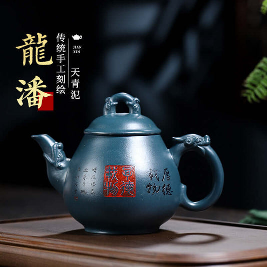 Handmade Yixing purple sand teapot in dark blue finish, featuring traditional engraving and unique dragon handles.