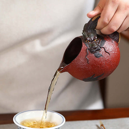 Handmade Yixing purple sand fair cup with dragon design, pouring tea into a cup, showcasing traditional craftsmanship.