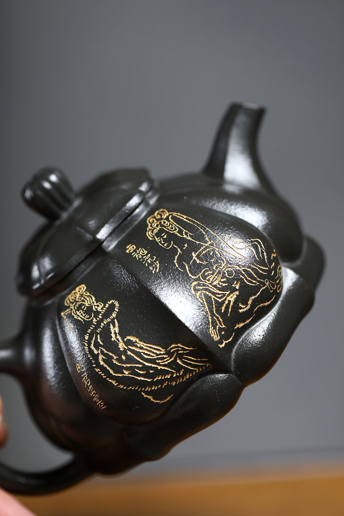 Handmade Yixing purple sand teapot featuring elegant gold detailing and unique curvature, showcasing fine craftsmanship.