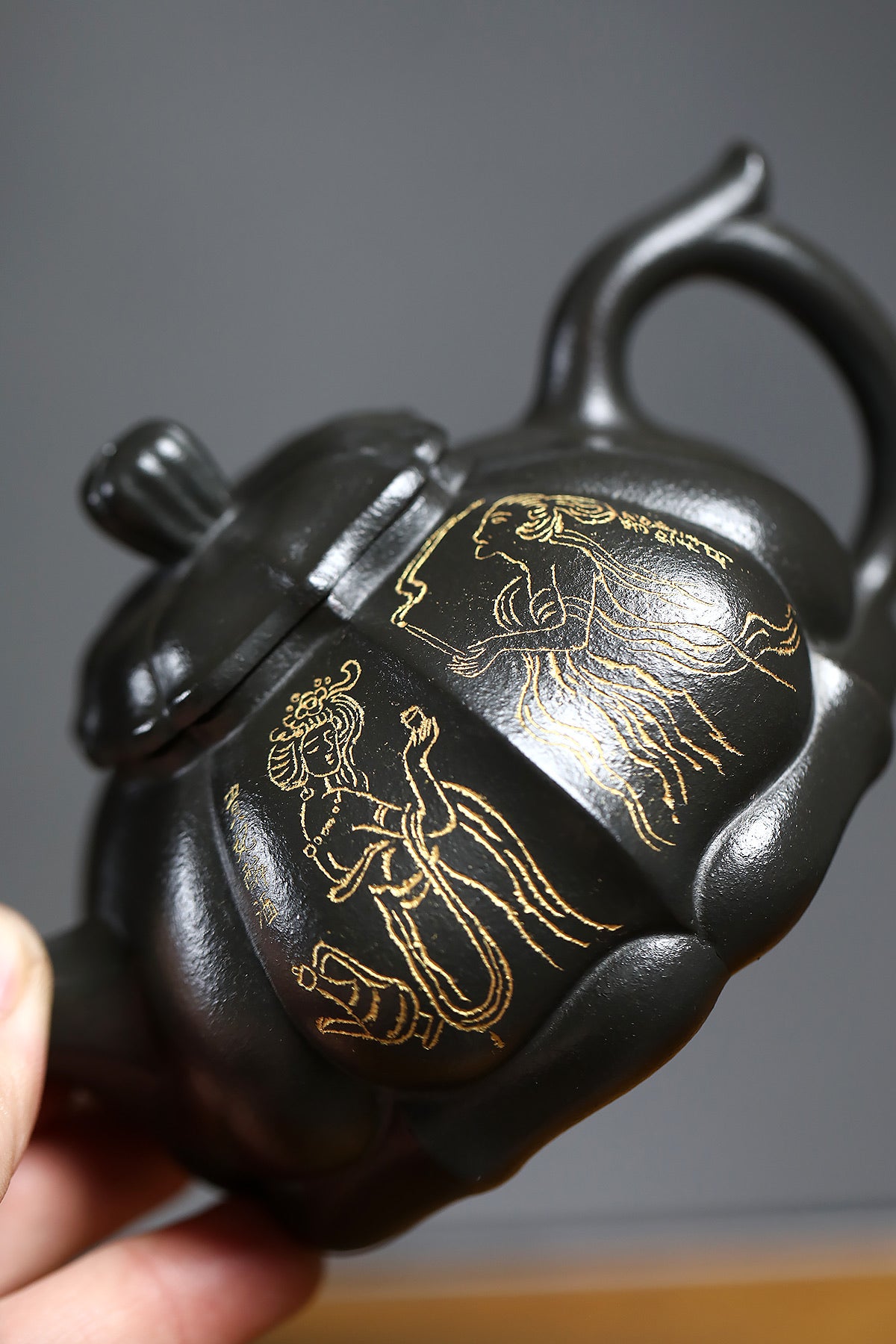 Handmade Yixing purple sand teapot with golden character illustrations, showcasing traditional craftsmanship and art.