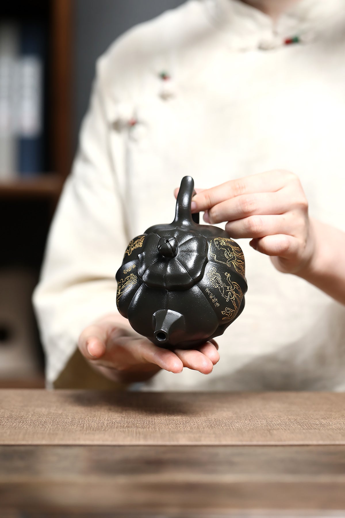 Handmade Yixing purple sand teapot being held, showcasing intricate design and craftsmanship.