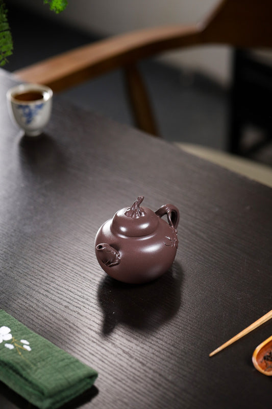 Handmade Yixing purple sand teapot displayed on a wooden table, showcasing its unique design and craftsmanship.