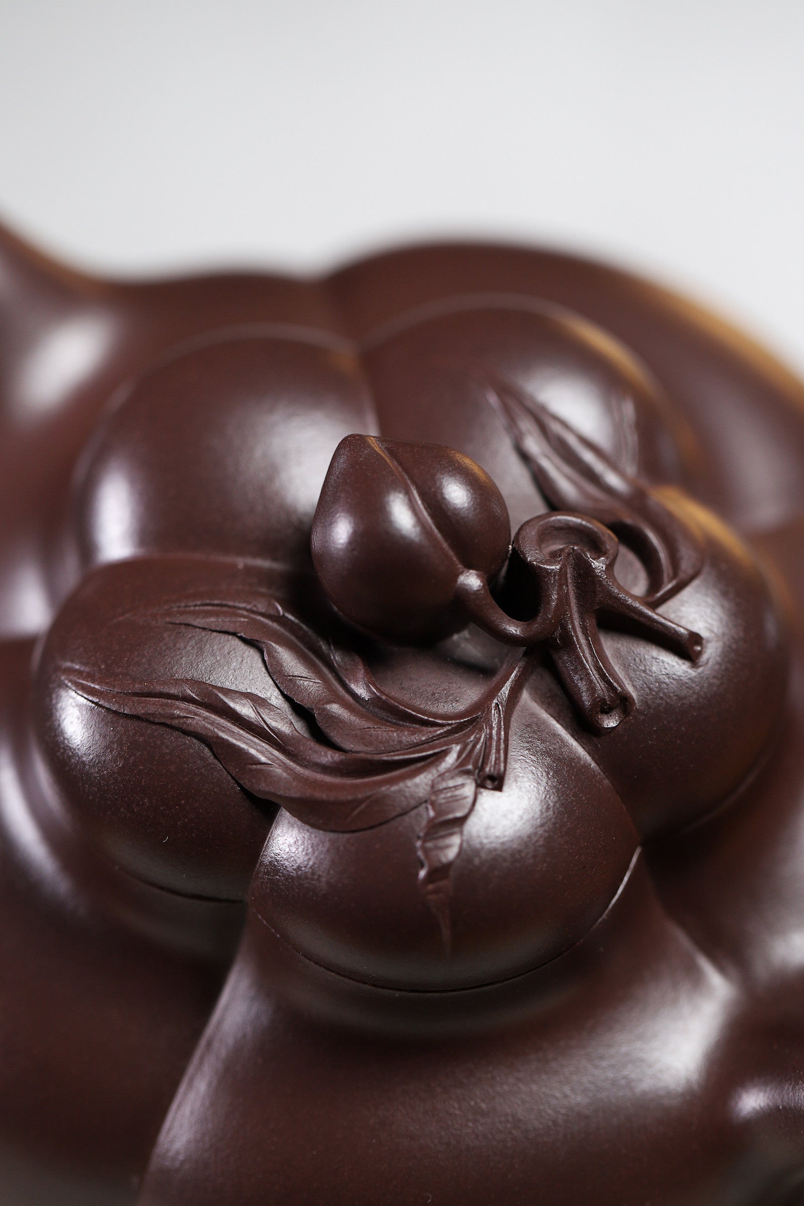 Handmade Yixing purple sand teapot lid with intricate peach motif, showcasing fine craftsmanship and details.