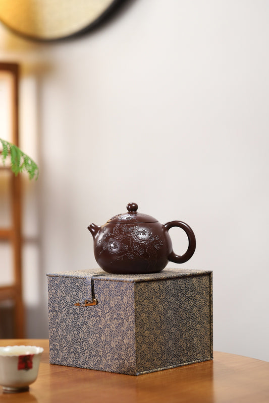 Handmade Yixing purple sand teapot on a decorative box, showcasing its elegant design and unique craftsmanship.
