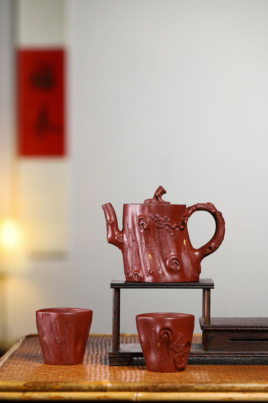 Handmade Yixing purple sand teapot set with pine tree design, includes one teapot and two cups, elegant craftsmanship.