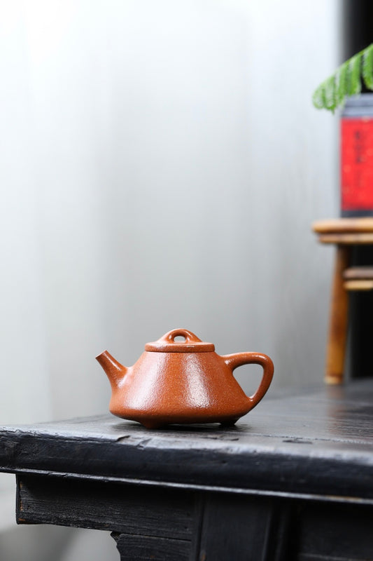 Handmade Yixing purple sand teapot displayed on a wooden table, showcasing its unique craftsmanship and design.