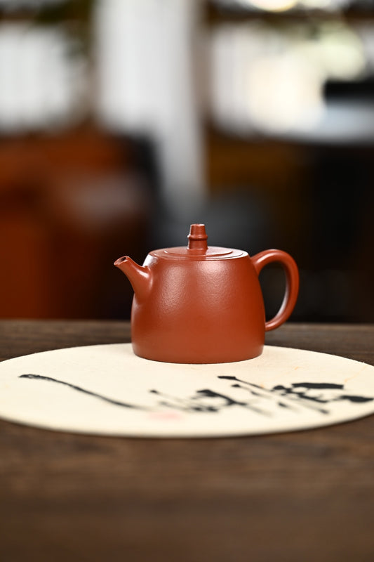 Handmade Yixing purple sand teapot on a decorative mat, highlighting its unique design and craftsmanship.