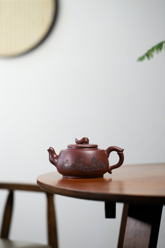 Handmade Yixing purple sand teapot with intricate design, displayed on a wooden table.