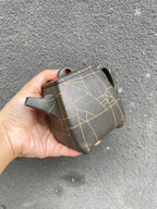 High stone teapot by Yang Junbao held in hand, featuring unique crackle design and handcrafted details.