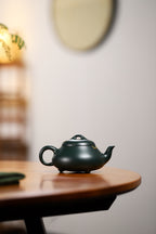 Chinese purple clay teapot with gold and silver inlay on a wooden table, showcasing its elegant design.