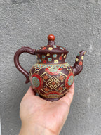 Yixing purple clay teapot with enamel decoration, handcrafted with intricate floral designs and a smooth finish.