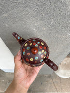 Yixing purple clay teapot with enamel decoration, top view, showcasing floral designs and handle.