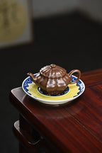 Handcrafted purple clay teapot 200cc displayed on a plate with intricate design, highlighting its unique form and craftsmanship.