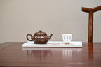 Handcrafted purple clay teapot 200cc elegantly displayed on a tray with a tea cup, highlighting traditional Yixing craftsmanship.
